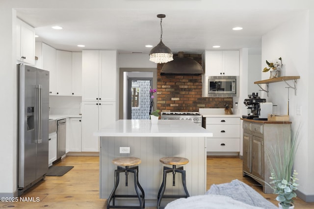 7530 N Rain Valley Rd, Flagstaff, AZ 86004 - kitchen with appliances with stainless steel finishes, wall chimney range hood, light wood-type flooring, a kitchen breakfast bar, and recessed lighting