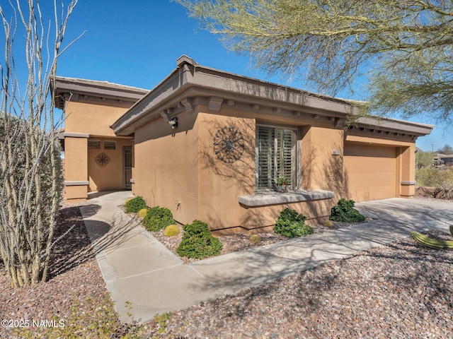 view of property exterior with a garage, driveway, and stucco siding