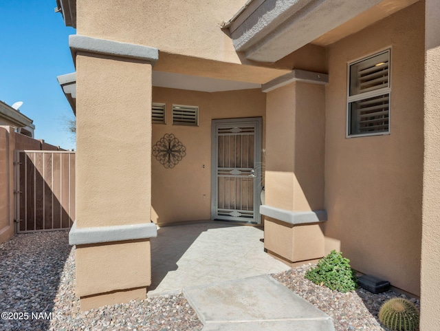 property entrance featuring a patio, fence, a gate, and stucco siding