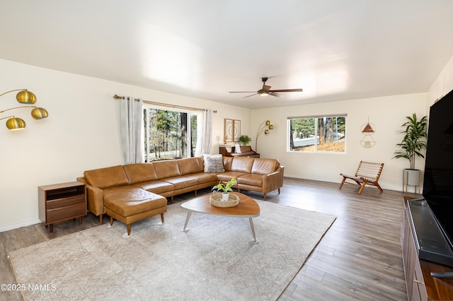 living area with a ceiling fan, baseboards, and wood finished floors