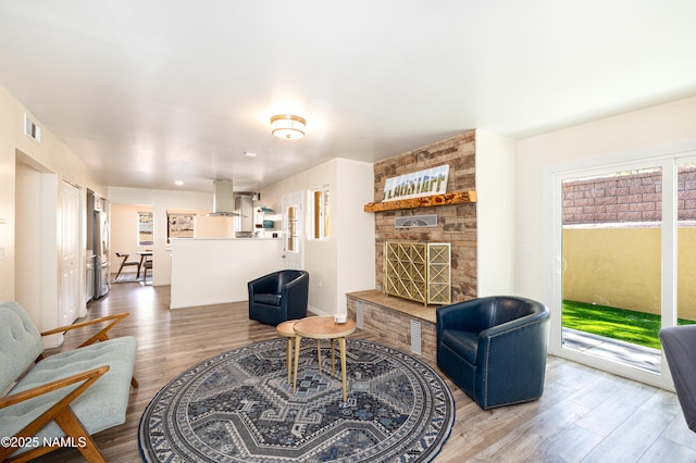 living area featuring a fireplace, wood finished floors, visible vents, and baseboards