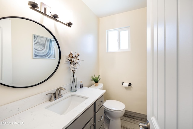 half bathroom featuring vanity, toilet, and wood finished floors