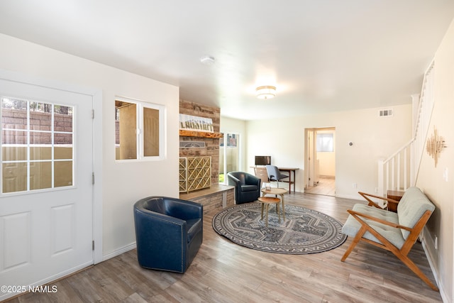 living area with stairs, wood finished floors, visible vents, and baseboards