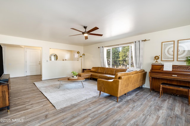 living room featuring wood finished floors, a ceiling fan, and baseboards