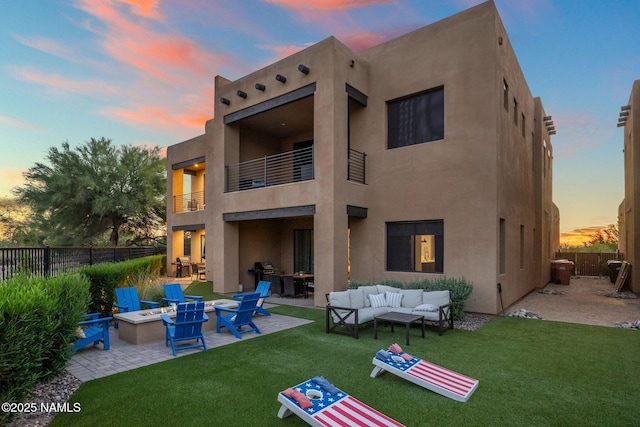 10299 E White Feather Ln, Scottsdale, AZ 85262 - back of property at dusk featuring a balcony, an outdoor living space with a fire pit, stucco siding, and a patio