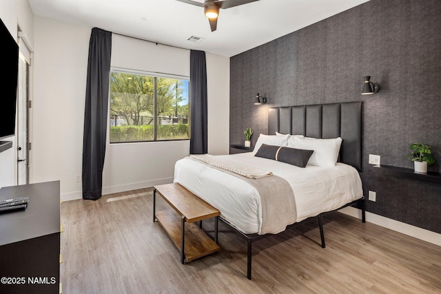10299 E White Feather Ln, Scottsdale, AZ 85262 - bedroom featuring an accent wall, light wood-style floors, wallpapered walls, and a ceiling fan