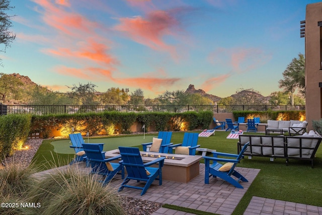 10299 E White Feather Ln, Scottsdale, AZ 85262 - patio terrace at dusk with an outdoor living space with a fire pit, a patio area, a fenced backyard, and a mountain view