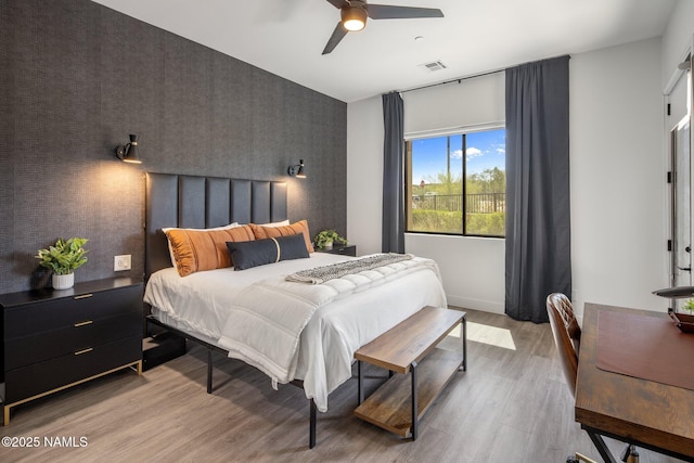 10299 E White Feather Ln, Scottsdale, AZ 85262 - bedroom with an accent wall, wallpapered walls, light wood-type flooring, and ceiling fan