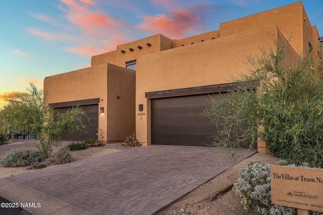 10299 E White Feather Ln, Scottsdale, AZ 85262 - pueblo revival-style home with decorative driveway, stucco siding, and a garage
