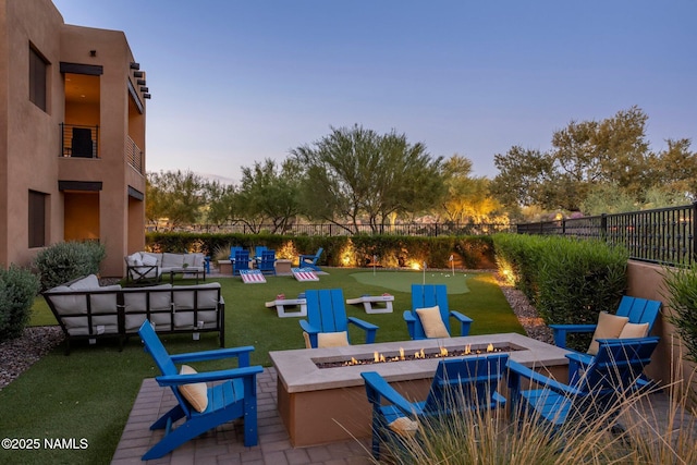 10299 E White Feather Ln, Scottsdale, AZ 85262 - patio terrace at dusk featuring a putting green, an outdoor living space with a fire pit, and a patio area