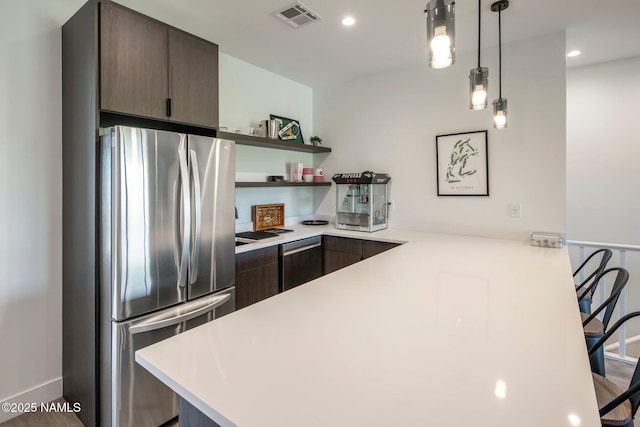 10299 E White Feather Ln, Scottsdale, AZ 85262 - kitchen featuring appliances with stainless steel finishes, light countertops, a peninsula, open shelves, and dark brown cabinets