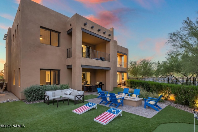 10299 E White Feather Ln, Scottsdale, AZ 85262 - back of house at dusk with a balcony, an outdoor living space with a fire pit, a patio, and stucco siding