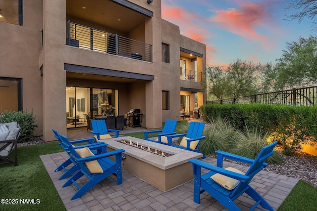 10299 E White Feather Ln, Scottsdale, AZ 85262 - patio terrace at dusk with a balcony, a patio, an outdoor living space with a fire pit, and a grill