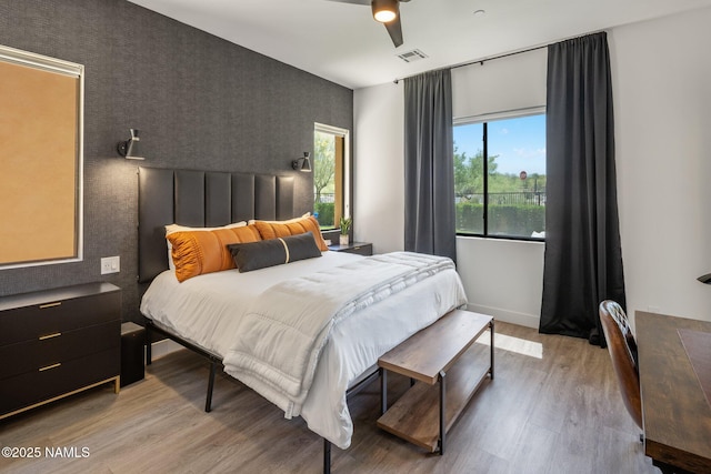 10299 E White Feather Ln, Scottsdale, AZ 85262 - bedroom featuring an accent wall, wallpapered walls, light wood-style flooring, and a ceiling fan