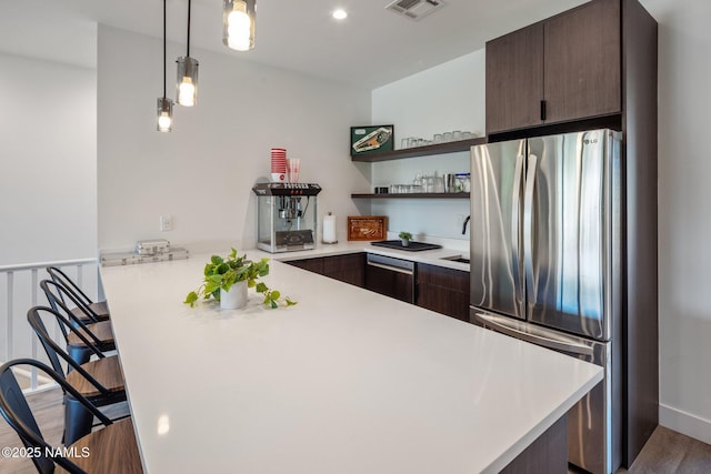 10299 E White Feather Ln, Scottsdale, AZ 85262 - kitchen featuring stainless steel appliances, a peninsula, light countertops, dark brown cabinetry, and a breakfast bar