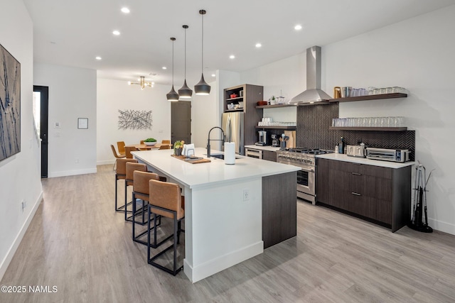 10299 E White Feather Ln, Scottsdale, AZ 85262 - kitchen featuring open shelves, appliances with stainless steel finishes, wall chimney range hood, a kitchen island with sink, and modern cabinets