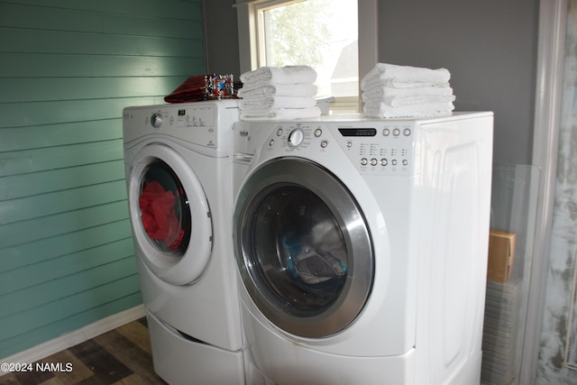 laundry room with wooden walls, dark hardwood / wood-style flooring, and washing machine and clothes dryer