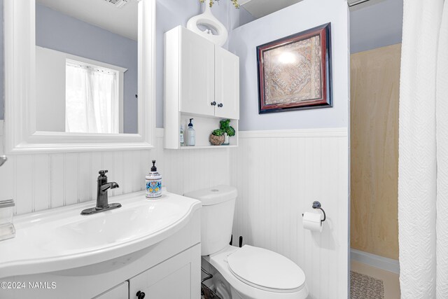 bathroom featuring vanity, toilet, and wood walls