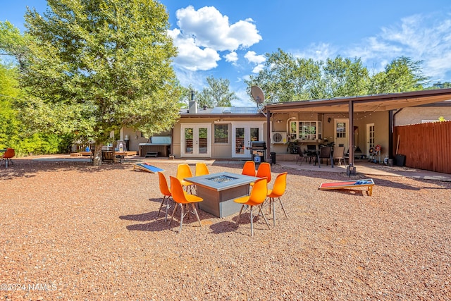 back of property with a patio, french doors, an outdoor fire pit, and a jacuzzi