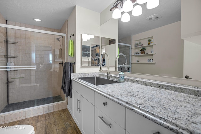 bathroom with a textured ceiling, an enclosed shower, and vanity