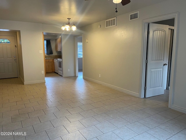 unfurnished living room with ceiling fan with notable chandelier and light tile patterned floors