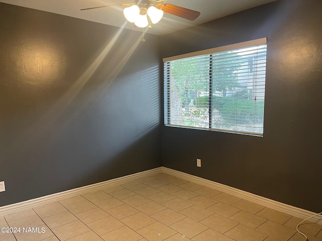 empty room featuring light tile patterned flooring, a healthy amount of sunlight, and ceiling fan