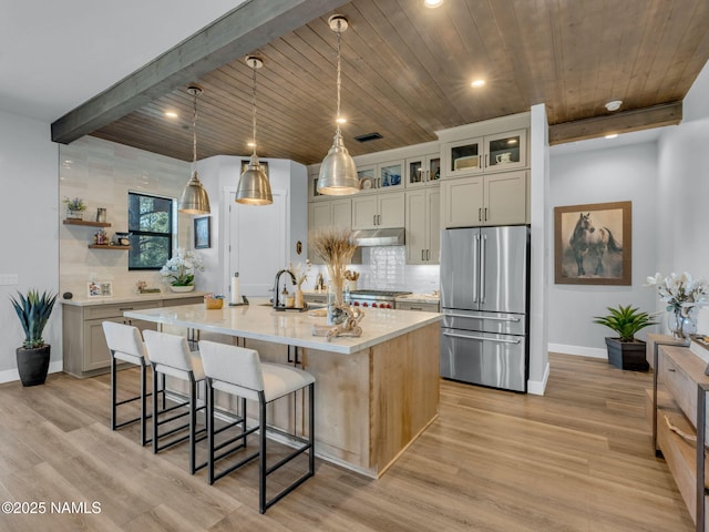 2566 S Cottonrose Ln, Flagstaff, AZ 86005 - kitchen with freestanding refrigerator, under cabinet range hood, light countertops, decorative backsplash, and wooden ceiling with exposed beams