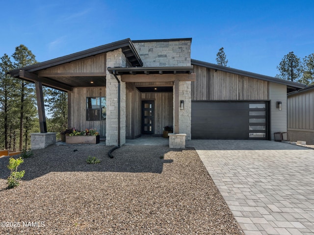 2566 S Cottonrose Ln, Flagstaff, AZ 86005 - contemporary house with stone siding, an attached garage, and driveway