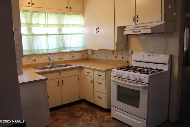 620 W Elm St, Winslow, AZ 86047 - kitchen with white range with gas cooktop, under cabinet range hood, light countertops, white cabinetry, and tasteful backsplash
