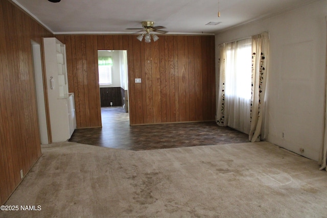 620 W Elm St, Winslow, AZ 86047 - carpeted spare room featuring wood walls, ornamental molding, and a ceiling fan
