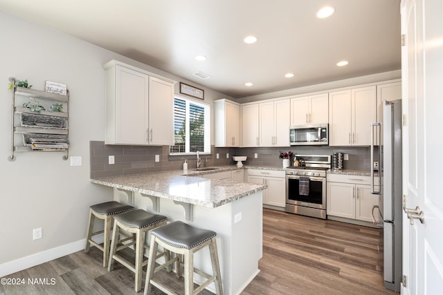 2845 W Hare Dr, Flagstaff, AZ 86001 - kitchen featuring a peninsula, a sink, tasteful backsplash, dark wood finished floors, and appliances with stainless steel finishes