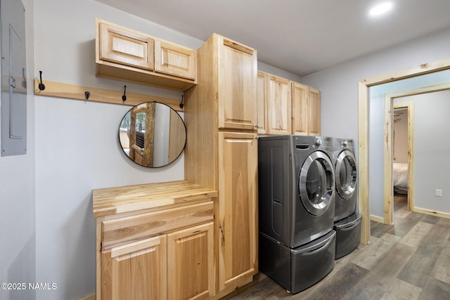 laundry room with baseboards, electric panel, washing machine and dryer, and wood finished floors