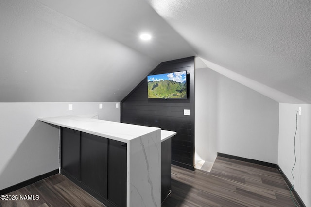bonus room with dark wood-type flooring, baseboards, and vaulted ceiling