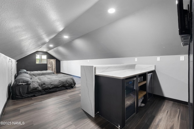 bedroom with baseboards, a textured ceiling, wood finished floors, and lofted ceiling