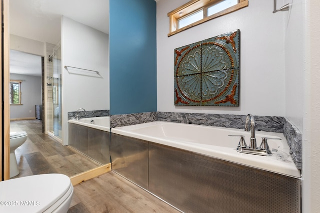 bathroom featuring a stall shower, a bath, wood finished floors, and toilet