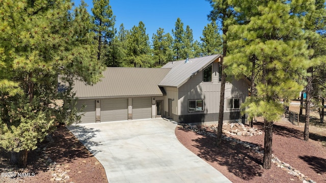 chalet / cabin with a garage, metal roof, and concrete driveway