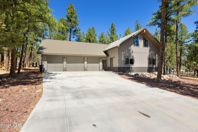 view of front of house featuring an attached garage, board and batten siding, driveway, and metal roof