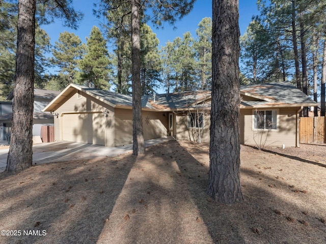 view of front of home with driveway, an attached garage, and fence