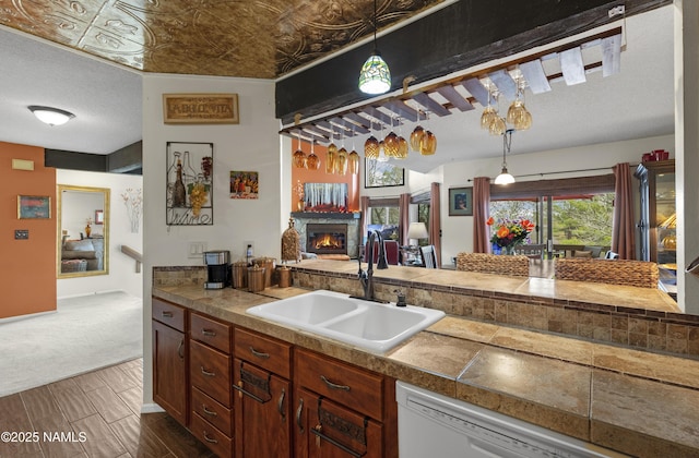 kitchen with sink, dishwasher, hanging light fixtures, and a textured ceiling