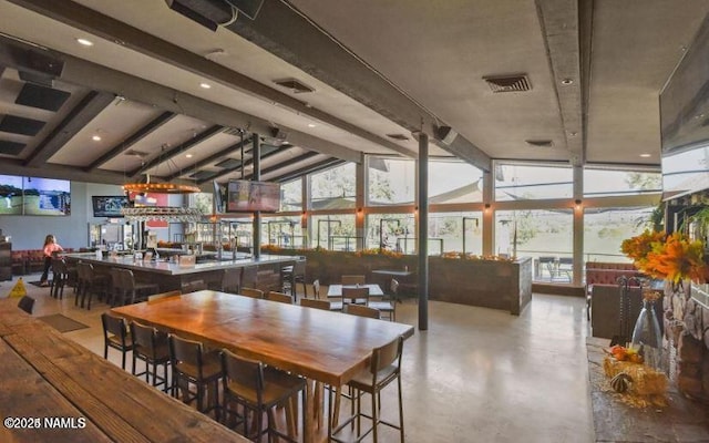 dining room with a wall of windows, vaulted ceiling, bar, and a healthy amount of sunlight