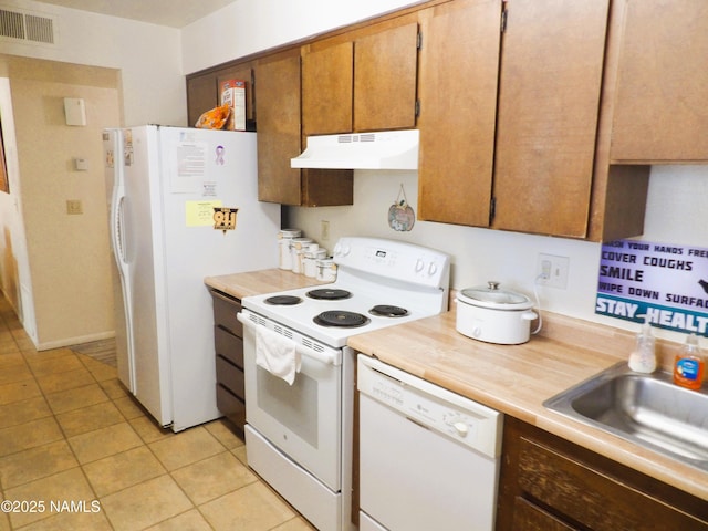 kitchen with light tile patterned floors, under cabinet range hood, white appliances, visible vents, and light countertops