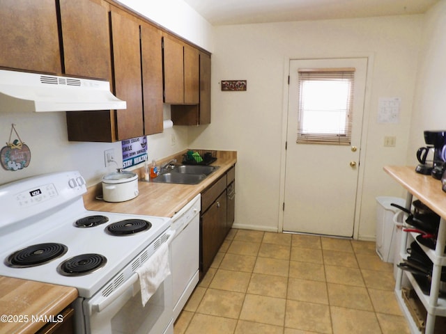 kitchen with white appliances, light tile patterned floors, light countertops, under cabinet range hood, and a sink