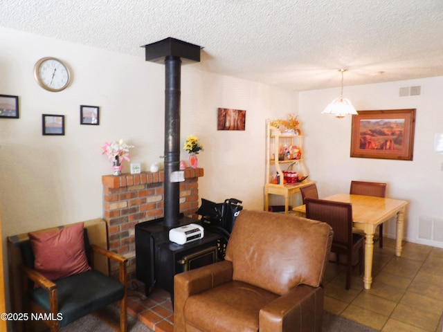 interior space with a wood stove, visible vents, and a textured ceiling