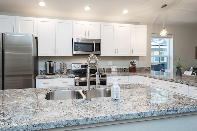 kitchen with decorative light fixtures, white cabinets, light stone counters, and appliances with stainless steel finishes