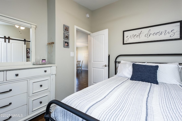 bedroom featuring a barn door and dark hardwood / wood-style flooring