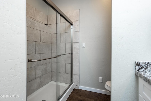 bathroom with wood-type flooring, toilet, walk in shower, and vanity