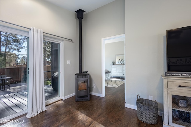 interior space with a wood stove, dark hardwood / wood-style floors, and a towering ceiling