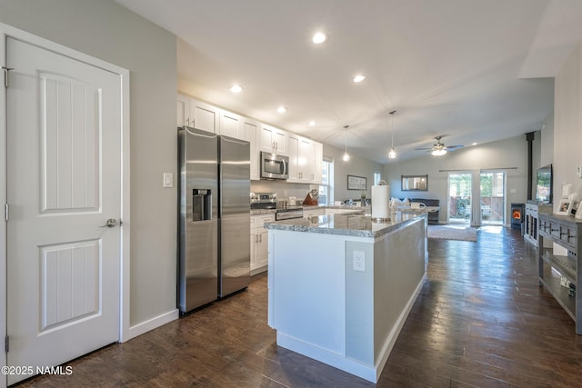 kitchen featuring light stone countertops, appliances with stainless steel finishes, white cabinets, vaulted ceiling, and dark hardwood / wood-style floors