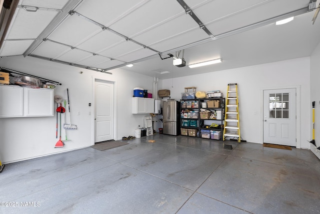 garage with a garage door opener and freestanding refrigerator