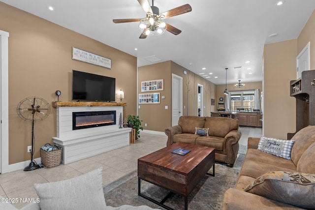 living room with recessed lighting, light tile patterned flooring, a glass covered fireplace, and baseboards